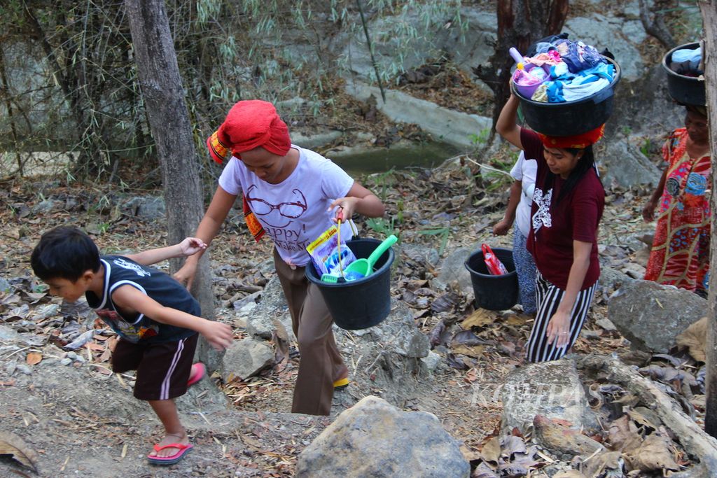 Jalanan menanjak harus dilalui warga seusai mencuci pakaian di air Kali Babeko yang keruh di Desa Manulea, Kecamatan Sasitamean, Kabupaten Malaka, Nusa Tenggara Timur, Rabu (21/10/2020). 