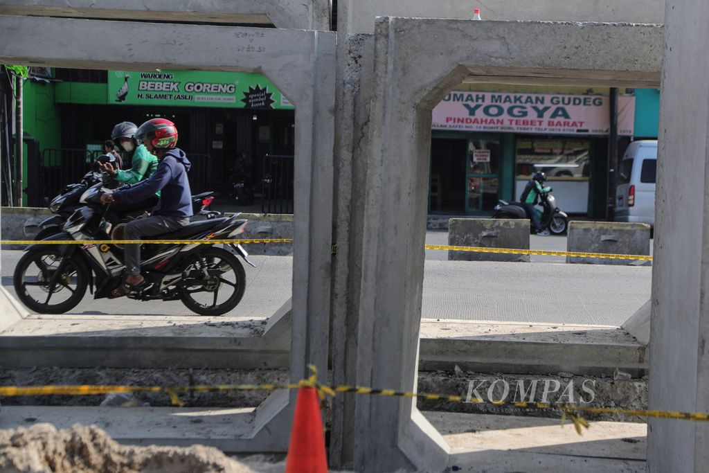 Pengendara sepeda motor melintas di samping boks saluran drainase atau <i>box culvert</i> di Jalan KH Abdullah Syafei, Jakarta, Jumat (14/7/2023).