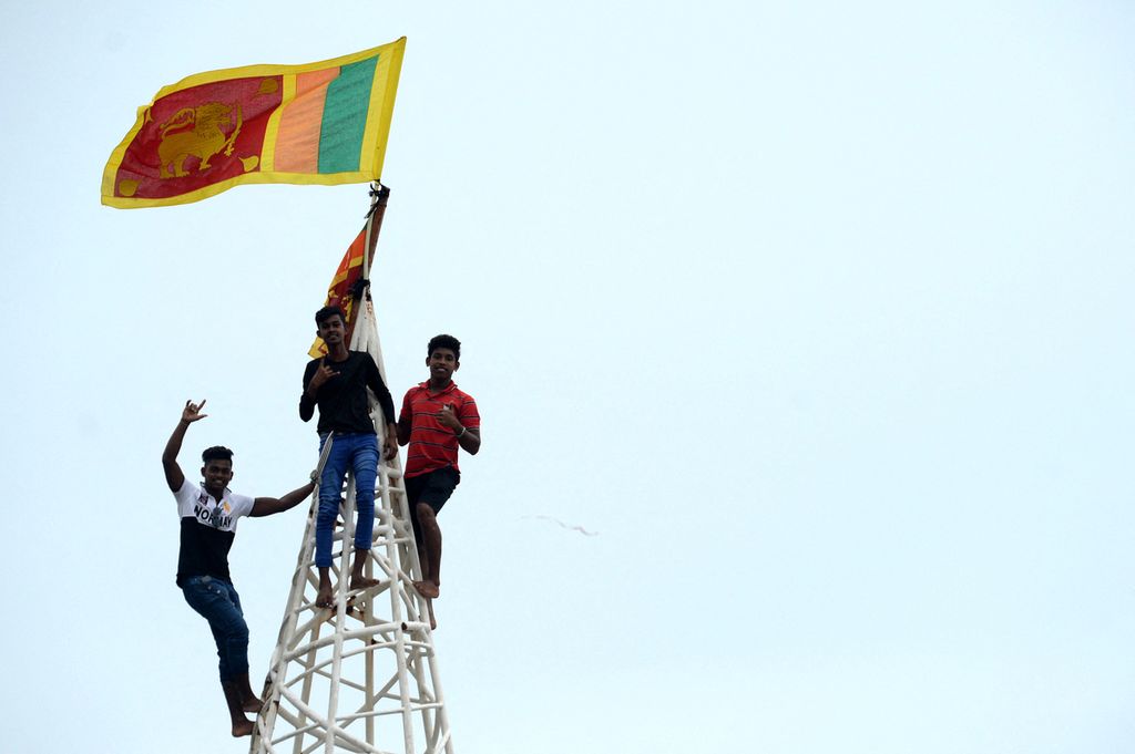 Pemuda mengibarkan bendera nasional Sri Lanka setelah memanjat menara dekat Sekretariat Presiden di Colombo, Senin (11/7/2022).