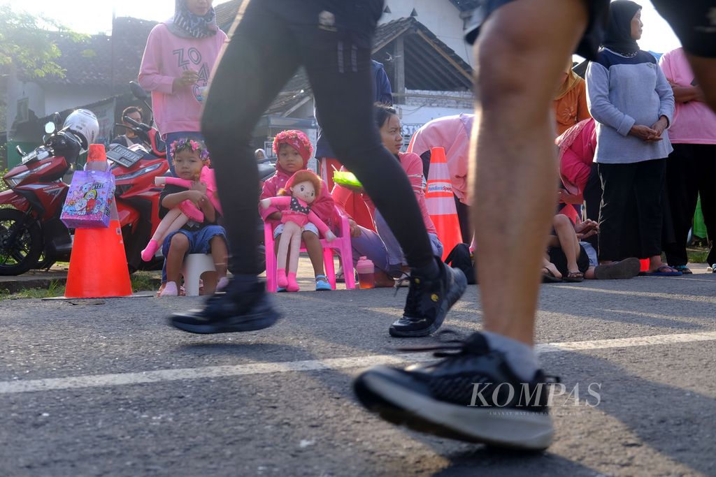 Warga menonton para pelari yang menyelesaikan Borobudur Marathon 2022 Powered by Bank kategori Tilik Candi yang melewati depan rumah mereka di sekitar kompleks Candi Borobudur, Magelang, Jawa Tengah, Minggu (12/11/2022). Sebanyak 4.552 pelari mengikuti lomba lari dengan jarak 21,097 kilometer atau separuh maraton. 