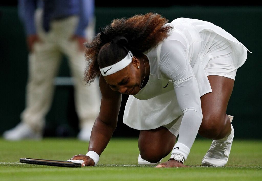 Serena Williams terjatuh karena cedera <i>hamstring</i> sebelum mundur pada set pertama saat melawan Aliaksandra Sasnovich pada laga babak pertama Wimbeldon di All England Lawn Tennis and Croquet Club, London, 29 Juni 2021. Cedera itu membuat Serena absen selama satu tahun.