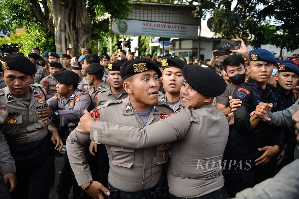 Polisi melerai rekannya yang tersulut emosi kepada massa aksi saat ricuh pecah di depan Pengadilan Negeri Jakarta Timur, Kamis (8/6/2023).  