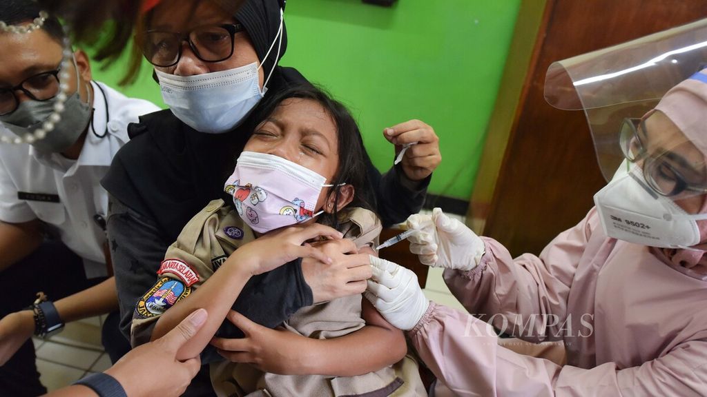 Petugas medis menyuntikkan vaksin Covid-19 kepada siswa di SD Negeri Ulujami 01, Pesanggrahan, Jakarta Selatan, Rabu (15/12/2021). Pada hari kedua pelaksanaan vaksinasi Covid-19 untuk anak usia 6-11 tahun di tempat tersebut diikuti oleh 387 anak. Pemerintah mencatat ada sekitar 26,5 juta anak usia 6 tahun hingga 11 tahun yang menjadi target vaksinasi Covid-19. Vaksinasi anak usia 6-11 tahun ini direncanakan dilakukan secara bertahap. Pada tahap pertama, vaksinasi akan dilaksanakan di provinsi dan kabupaten/kota dengan kriteria cakupan vaksinasi dosis 1 di atas 70 persen dan cakupan vaksinasi warga lansia di atas 60 persen.