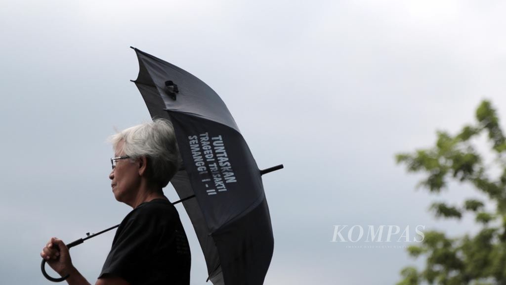 Maria Catarina Sumarsih dengan payung hitamnya saat mengelar Aksi Kamisan di depan Istana Negara, Jakarta, Kamis (6/12/2018). 