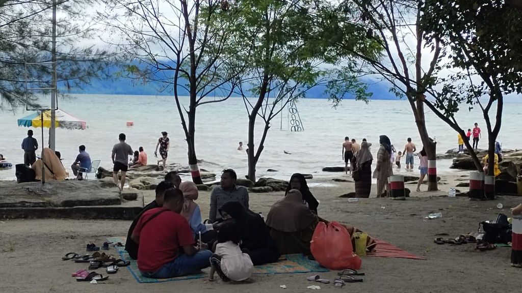 Pengunjung memadati Pantai Batu Hoda di Kabupaten Samosir, Sumatera Utara, Selasa (3/5/2022). Sejumlah destinasi di kawasan Danau Toba menjadi tujuan liburan pada Lebaran hari kedua.