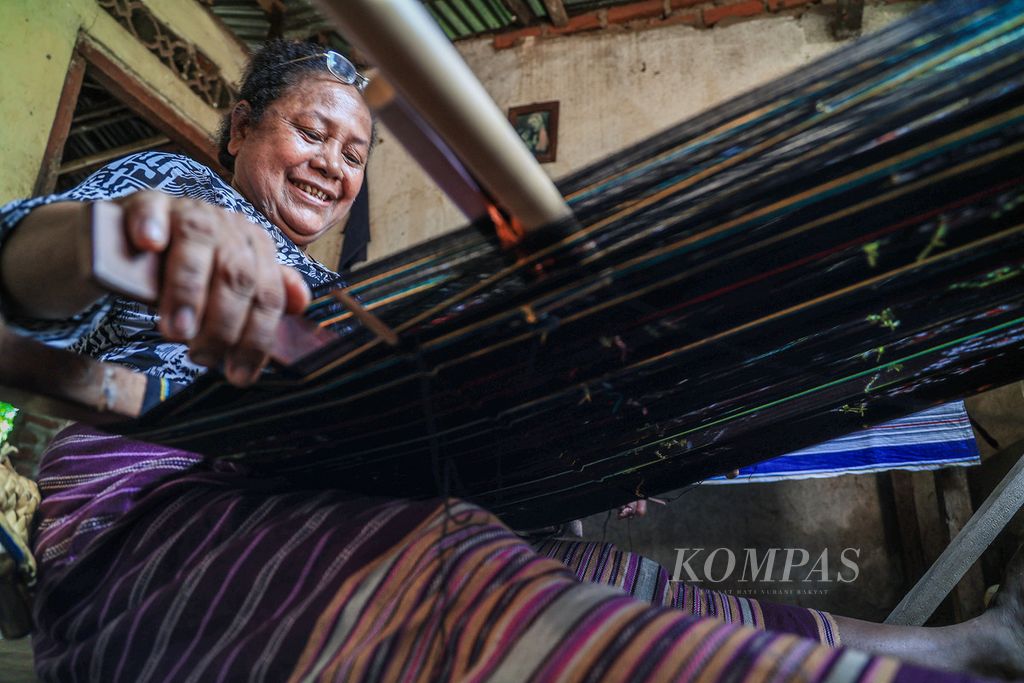 Katarina Kremo Tapoona (57) menenun kain di rumahnya di Desa Lamalera A, Kabupaten Lembata, Nusa Tenggara Timur, Kamis (23/11/2023). Tradisi berburu paus di Lamalera salah satunya mewujud dalam obyek kebudayaan pengetahuan tradisional berupa menenun yang disebut <i>tani tenane</i>. 
