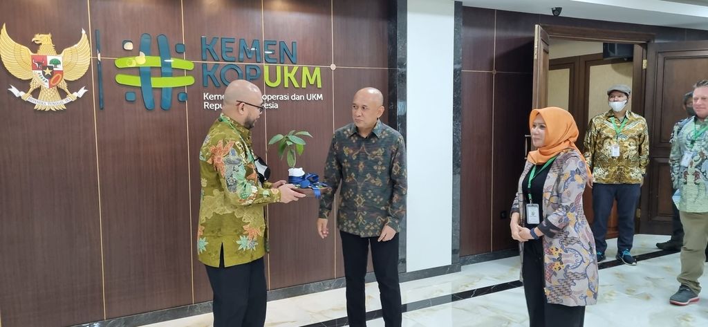 Ketua Koperasi Anugerah Bumi Hijau (Koprabu) Yohanis Cianes Waleyan (kiri) menyerahkan bibit tanaman kratom kepada Menteri Koperasi dan UKM Teten Masduki (tengah) di Kementerian Koperasi dan UKM, Jakarta, Rabu (10/8/2022). 