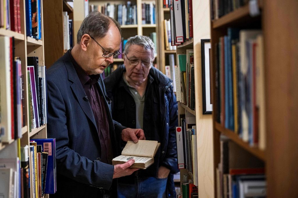 Clas Svahn (kiri) dan Anders Liljegren memandang sebuah buku di Archives for the Unexplained (AFU) di Norrkoping, Swedia, 12 Maret 2024. 