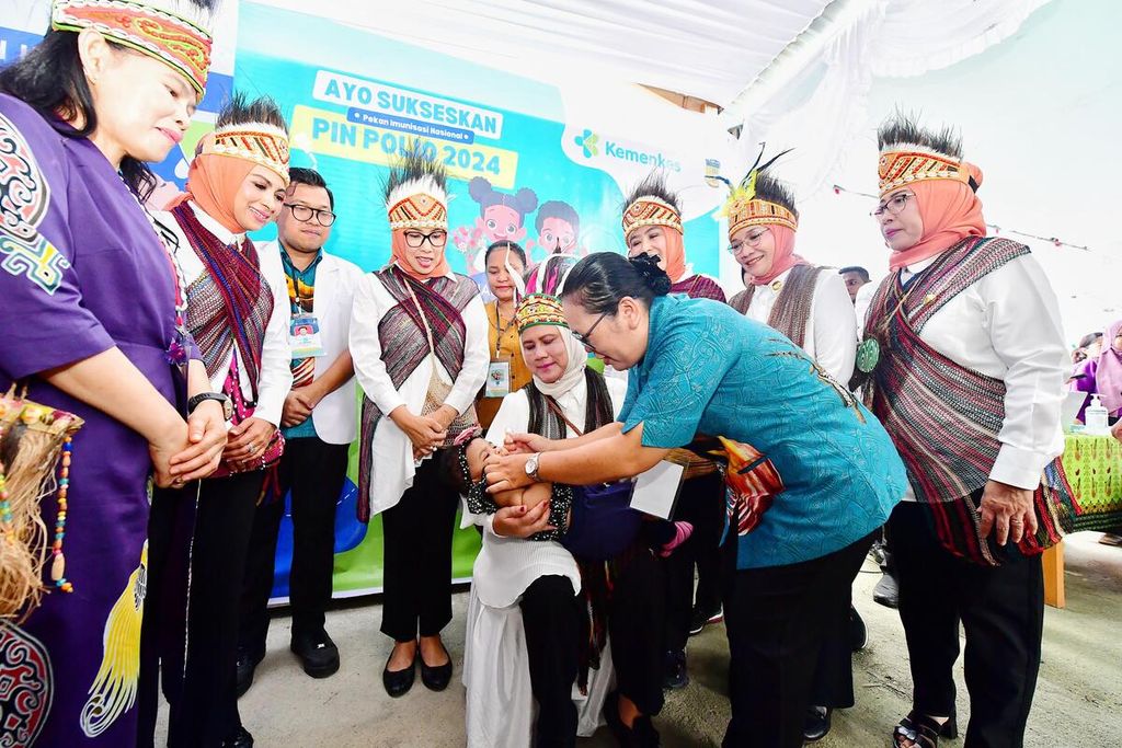 Nyonya Iriana Joko Widodo menggendong seorang anak yang akan mendapatkan vaksin polio di Posyandu Rajawali 3, kompleks Graha Nendali, Jalan Raya Sentani-Waena, Nendali, Kecamatan Sentani Timur, Kabupaten Jayapura, Selasa (23/7/2024).