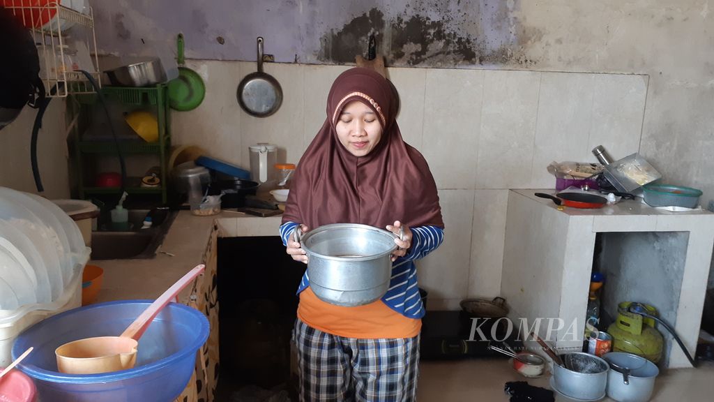 Seorang warga di bantaran Kali Ciliwung, Batu Ampar, Kramat JatI, Jakarta Timur, hendak memasak air tanah untuk keperluan minum, Minggu (13/8/2023).