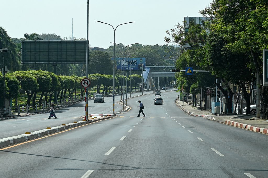 Pejalan kaki menyeberangi jalan yang nyaris kosong saat mogok sunyi untuk memprotes dan memperingati dua tahun kudeta militer Myanmar di Yangon, Myanmar, 1 Februari 2023. 
