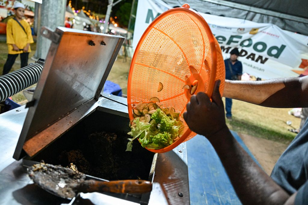 Pedagang makanan di bazar Ramadhan di Kuantan, Malaysia, menuang sampah makanan ke dalam mesin pembuat kompos, Rabu (3/4/2023).