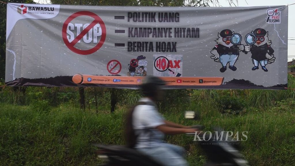 Pengendara melintas di sekitar spanduk yang dipasang Badan Pengawas Pemilihan Umum (Bawaslu) Jawa Timur di Jalan Raya Sukodono, Sidoarjo, Senin (11/12/2023). 