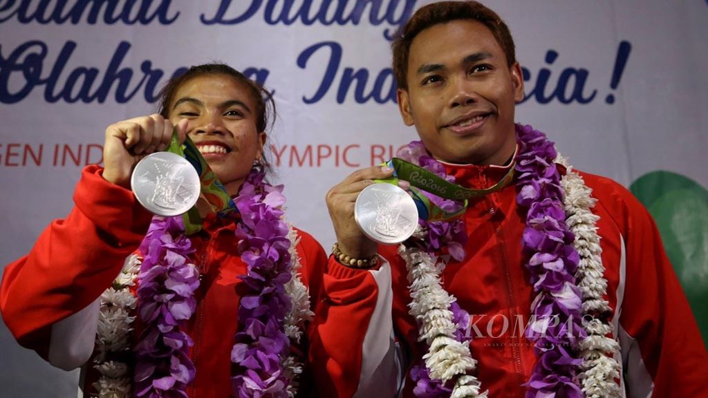 Lifter angkat besi Indonesia, Eko Yuli Irawan (kanan) dan Sri Wahyuni, menunjukkan medali perak yang mereka raih di Olimpiade Rio de Janeiro 2016 setibanya di Bandara Internasional Soekarno-Hatta, Tangerang, Banten, Minggu (14/8/2016).