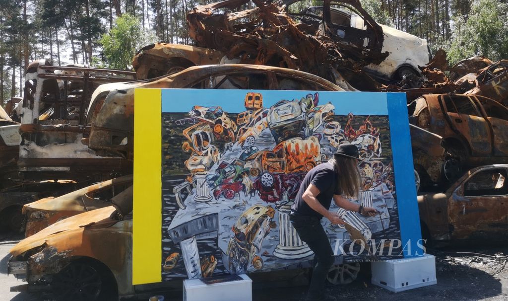George Gittoes, seniman asal Australia, melukis tumpukan bangkai mobil di Kota Irpin, Provinsi Kyiv, Ukraina, Senin (20/6/2022). George melukis jejak serangan Rusia ke Ukraina untuk menyebarkan pesan perdamaian mengenai kejamnya dampak perang. 