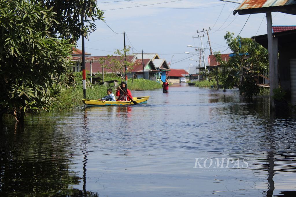 Seorang warga Kelurahan Palangka, Kota Palangkaraya, Kalimantan Tengah, menggunakan jukung atau sampan kayu untuk berangkat bekerja di tengah banjir yang terjadi, Jumat (10/2/2023). 
