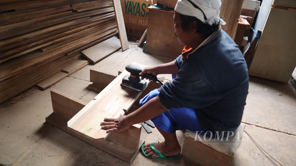 Seorang perajin menghaluskan bilah kayu untuk nisan makam di Yayasan Bunga Kemboja, Pejaten Timur, Pasar Minggu, Jakarta Selatan, Jumat (9/6/2023).