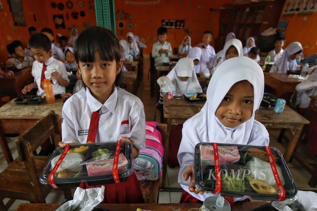 Dua siswa memperlihatkan porsi makanan bergizi gratis seharga Rp 14.500 di SDN Sentul 02 Kabupaten Bogor, Jawa Barat, Selasa (23/7/2024). Wakil presiden terpilih Gibran Rakabuming Raka memantau uji coba program makan bergizi gratis di SDN 02 dan 03 Sentul, Kabupaten Bogor, Jawa Barat. 