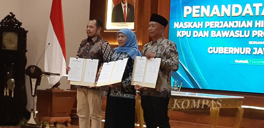 Ketua KPU Jatim Choirul Anam (kiri), Gubernur Jatim Khofifah Indar Parawansa (tengah), dan Ketua Bawaslu Jatim A Warits (kanan) menunjukkan naskah perjanjian hibah daerah Pilkada Jatim 2024 pada Kamis (7/12/2023) malam di Surabaya. 