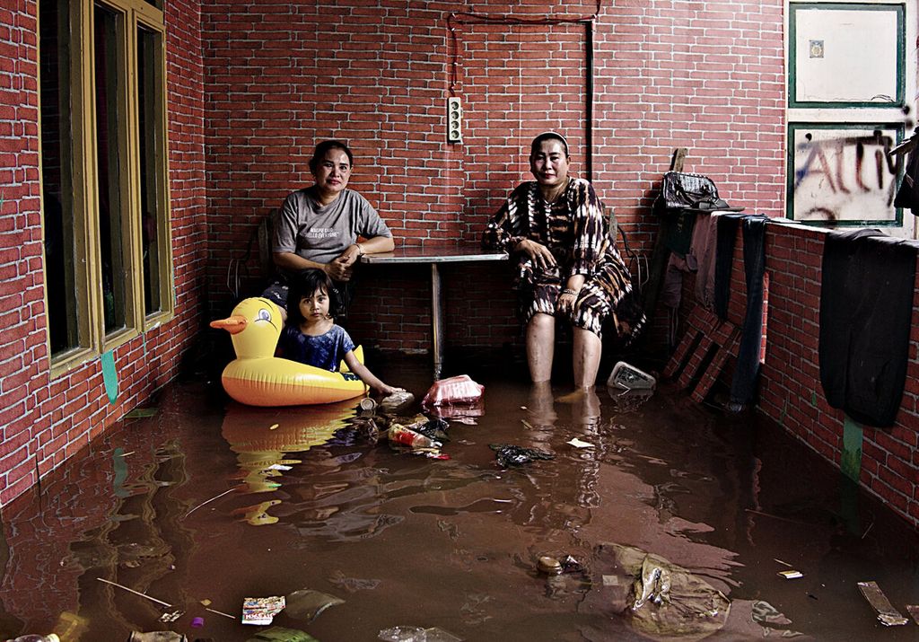 Nilam Sari, kiri, difoto bersama keluarganya di teras rumah yang tergenang luapan Sungai Kapuas, di Kampung Beting, Kelurahan Dalam Bugis, Kecamatan Pontianak Timur, Pontianak, Kalimantan Barat.