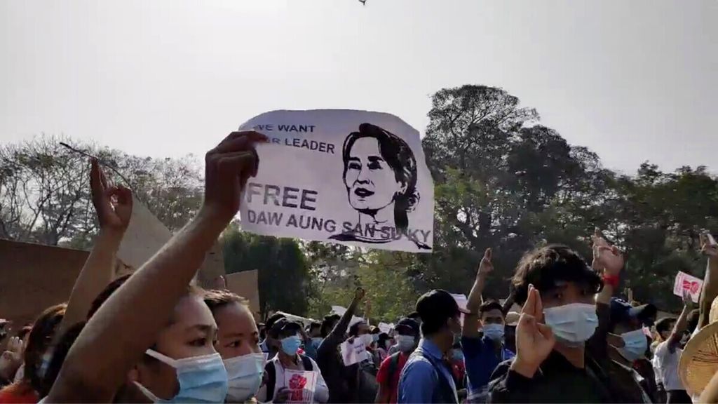 Foto dari tangkapan video yang disediakan Democratic Voice of Burma menunjukkan seorang pengunjuk rasa memegang poster bertuliskan Bebaskan Aung San Suu Kyi” di bawah foto pemimpin Myanmar yang kini ditahan junta militer Myanmar di Yangon, 7 Februari 2021. 