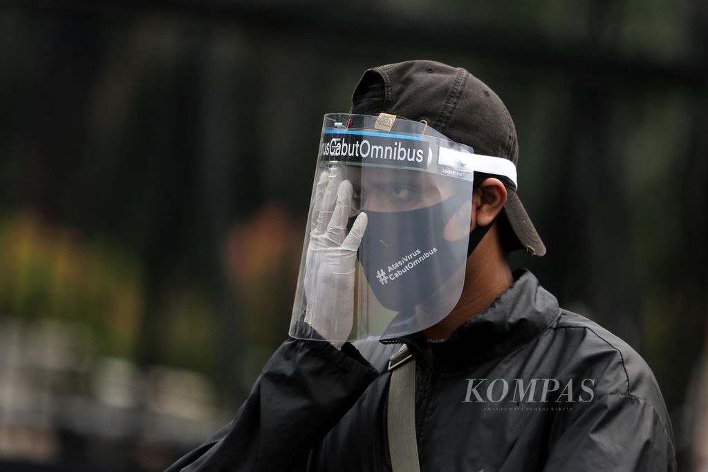 Aktivis dari gerakan #BersihkanIndonesia mengenakan masker dan pelindung wajah saat menggelar aksi penolakan terhadap Rancangan Undang-Undang Cipta Kerja di depan Gedung Parlemen, Jakarta, Selasa (14/7/2020). 