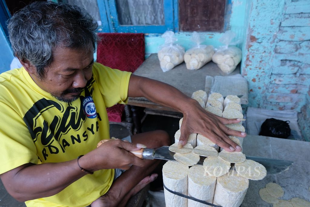 Budi, warga Kampung Sanan, Kota Malang, Sabtu (8/4/2023), mengiris tipis tempe untuk dibuat keripik. Di kampung ini, mayoritas warga terlibat dalam industri keripik, mulai dari pembuat tempe, pengiris, penggoreng keripik, hingga pemasok keripik tempe.
