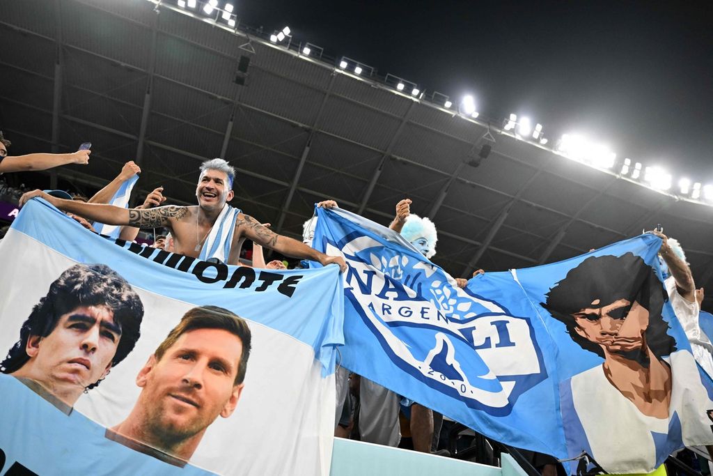 Fans Argentina membentangkan bendera bergambar mendiang Diego Maradona dan kapten Lionel Messi merayakan kemenangan 2-0 atas Polandia di penyisihan Grup C Piala Dunia Qatar di Stadion 974, Doha, Rabu (30/11/2022).