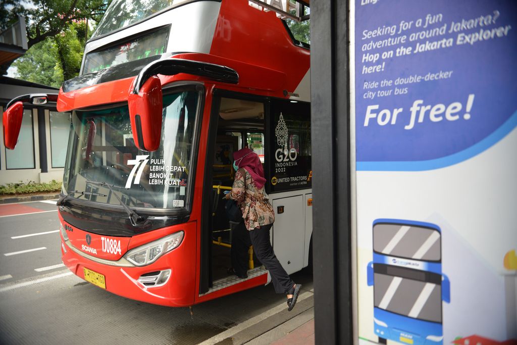 Seorang warga menaiki bus wisata Transjakarta di Jalan Medan Merdeka Selatan, Jakarta, Selasa (3/1/2023).