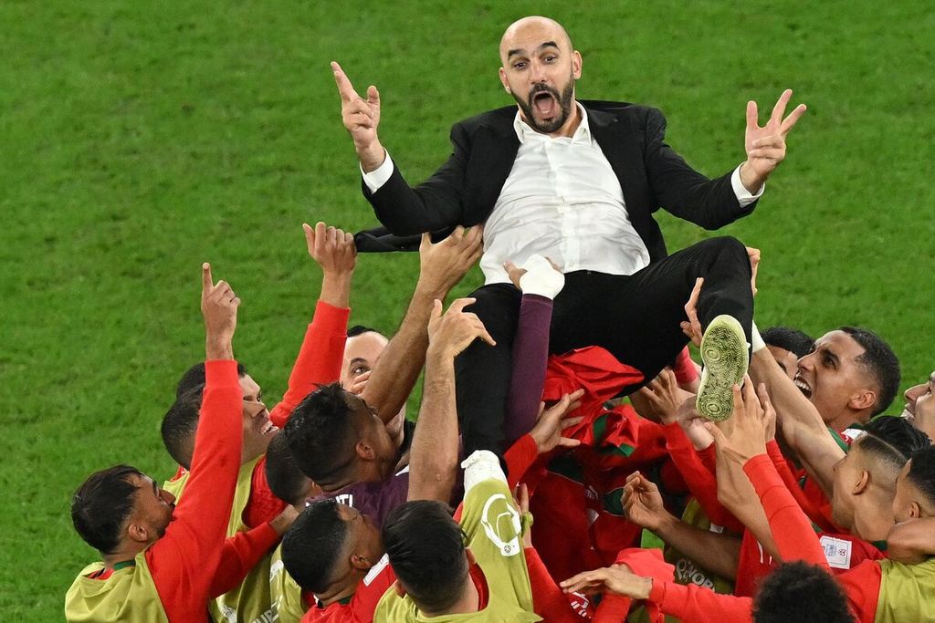para pemain Maroko melemparkan pelatih mereka Walid Regragui ke udara untuk emrayakan kemenangan mereka atas Spanyol pada laga babak 16 besar di Stadion Education City, Al-Rayyan, bagian barat Doha, Selasa (6/12/2022). 