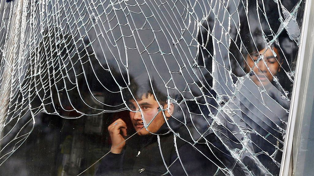 Seorang penjaga toko  memandang dari balik kaca jendela toko yang pecah, dekat lokasi serangan bom ambulans di Kabul, Afghanistan, yang menewaskan sedikitnya 103 orang, Sabtu (27/1). 