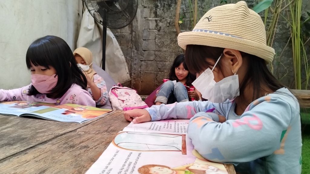 Anak-anak tengah menikmati buku bacaan anak bergambar dalam acara bertajuk membaca dan menulis bersama, di kawasan Cibubur, Kecamatan Ciracas, Jakarta Timur, Minggu (29/1/2023).