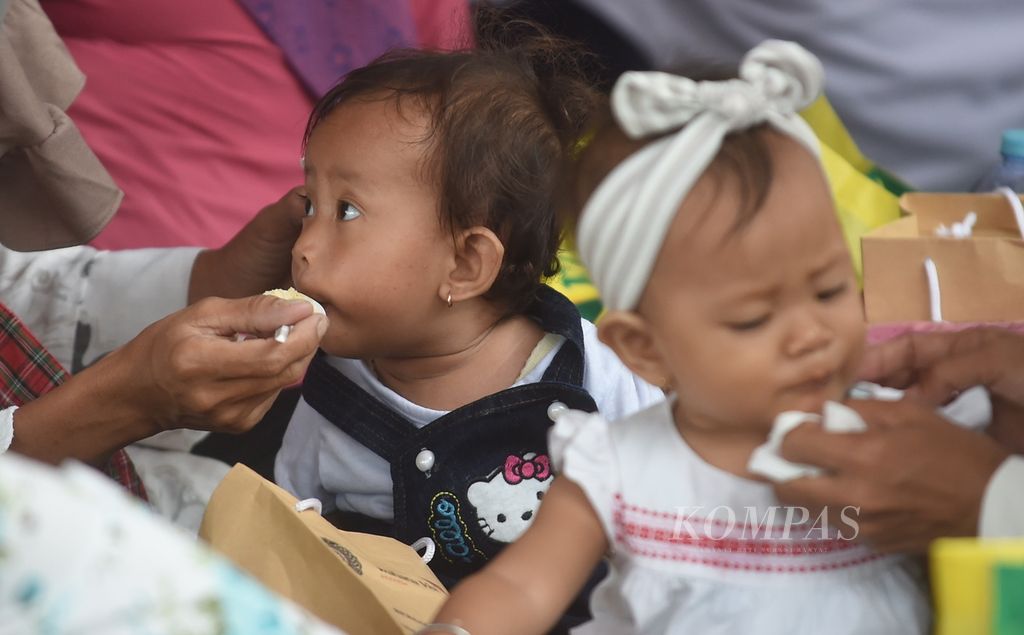Ibu memberi makan bayinya dengan bubur sehat saat peluncuran Gebyar Lomba Balita Sehat di halaman Balaikota Surabaya, Jawa Timur, Rabu (26/1/2022).  