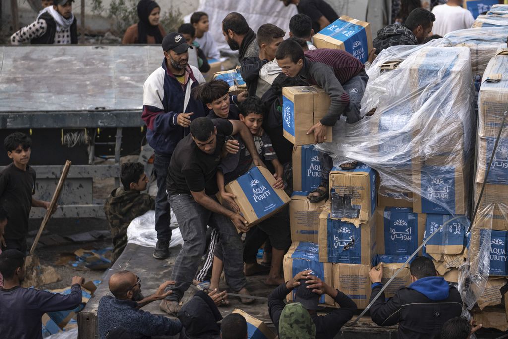 Warga Palestina berebut bantuan kemanusiaan yang dipasok dengan truk ke Jalur Gaza melewati Rafah pada 17 Desember 2023. 