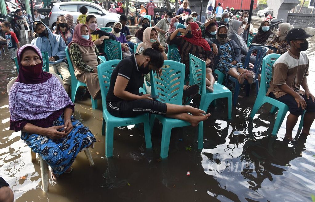 Warga antre mendapatkan bantuan langsung tunai (BLT) saat banjir rob di halaman Markas Koramil 0830/01 Krembangan, Kota Surabaya, Jawa Timur, 19 Mei 2022. Kemiskinan dan pengangguran masih menjadi problem besar di Jatim.