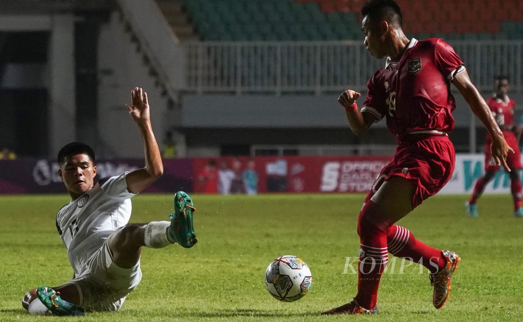Striker tim U-17 Indonesia, Muhammad Nabil Asyura (kanan), dihadang bek tim U-17 Guam, Nicholas Scott Moore (kiri), dalam laga kualifikasi Piala Asia U-17 2023 di Stadion Pakansari, Kabupaten Bogor, Jawa Barat, Senin (3/10/2022). Tim U-17 Indonesia unggul atas tim U-17 Guam dengan skor 14-0.  Indonesia akan menghadapi Uni Emirat Arab pada laga kedua, Rabu (5/10/2022) malam, di tempat yang sama.