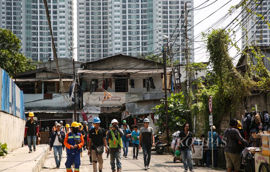 Pekerja berjalan menuju proyek seusai istirahat siang di kawasan Kebon Melati, Tanah Abang, Jakarta Pusat, Senin (31/7/2023). Proyek properti yang pesat di jakarta menyerap banyak tenaga kerja di sektor informal. 