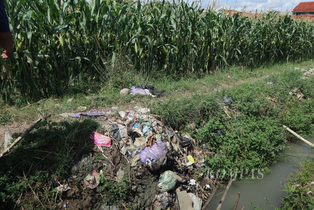 Sampah rumah tangga menumpuk di saluran irigasi dengan lahan jagung di Babakan, Kabupaten Cirebon, Jawa Barat, Minggu (3/7/2022). 