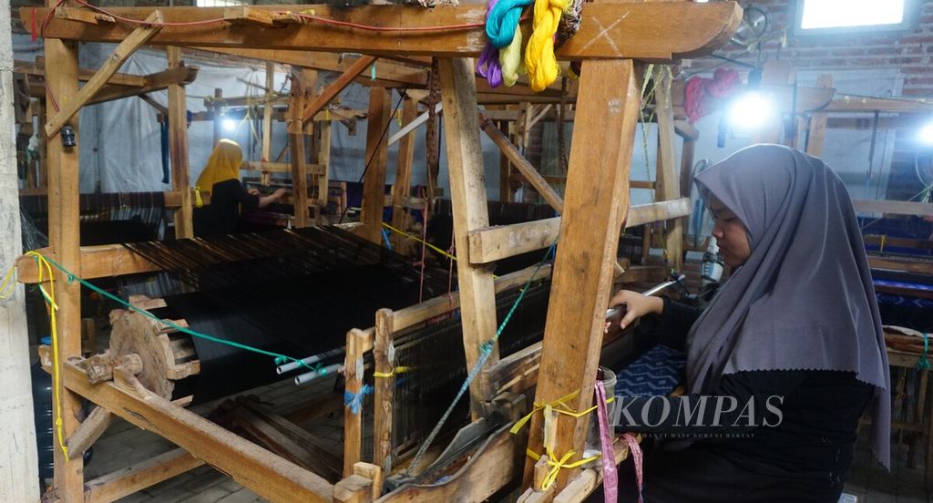 Seorang artisan petenun bekerja di rumah tenun ikat Medali Mas, Kota Kediri, Jawa Timur, Sabtu (14/10/2023). Artisan penenun baik lelaki maupun perempuan banyak menggantungkan hidup dari pekerjaan tersebut.