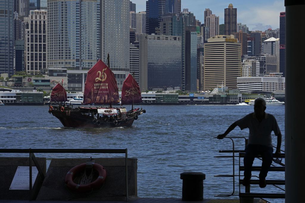 Sebuah perahu tradisional China melintas di depan Pelabuhan Victoria denga layar bergambar logo peringatan 25 tahun Hong Kong kembali ke China, Senin (27/6/2022).