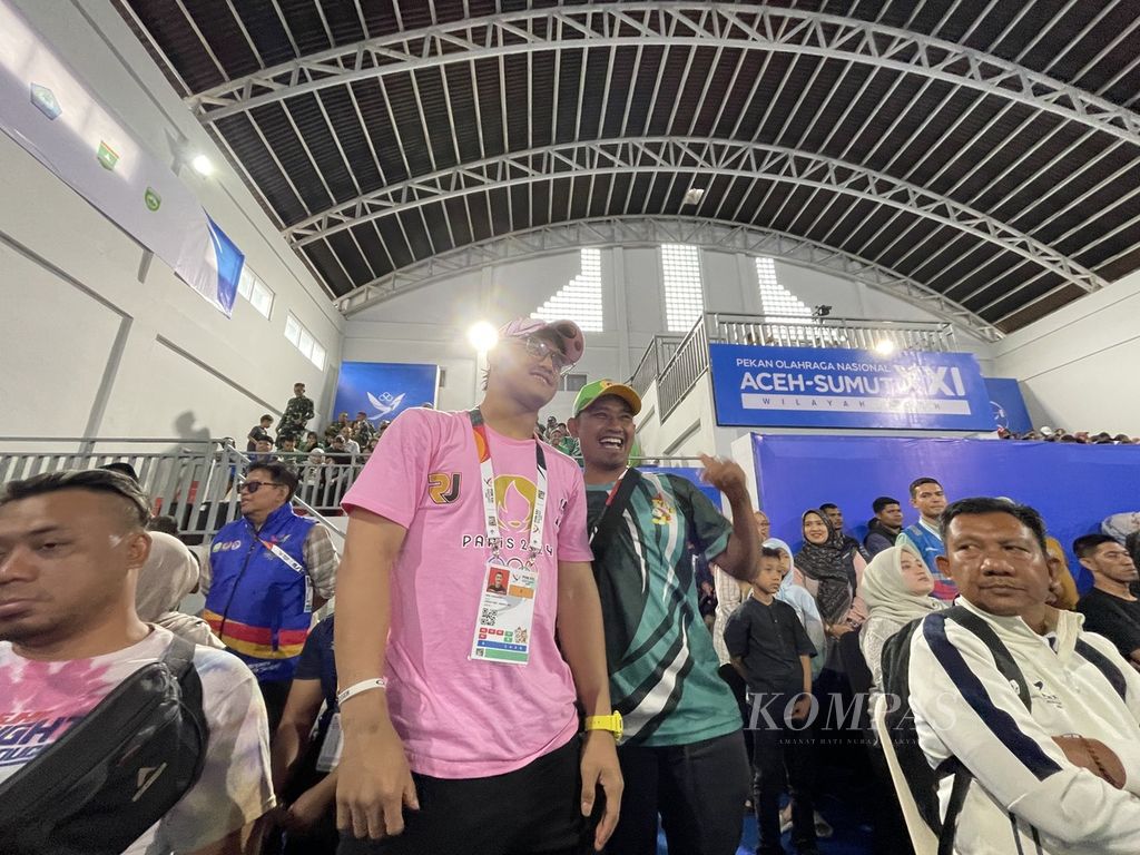 Lifter peraih medali emas Olimpiade Paris 2024, Rizki Juniansyah, melayani permintaan foto bersama saat berada di dalam arena angkat besi GOR Seuramoe, Banda Aceh, Aceh, Rabu (4/9/2024).