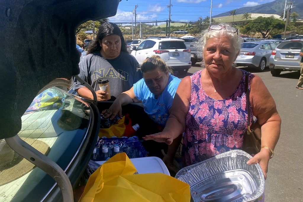 Vilma Reed (63), putrinya Amanda Hernandez (45), dan cucu Natanael Hernandez (18) memasukkan sumbangan untuk korban bencana kebakaran hutan ke dalam mobil mereka di tempat parkir Kompleks Peringatan Perang yang kini menjadi tempat berlindung dan pusat donasi, di Kahului, Maui, Hawaii, Sabtu (12/8/2023). 