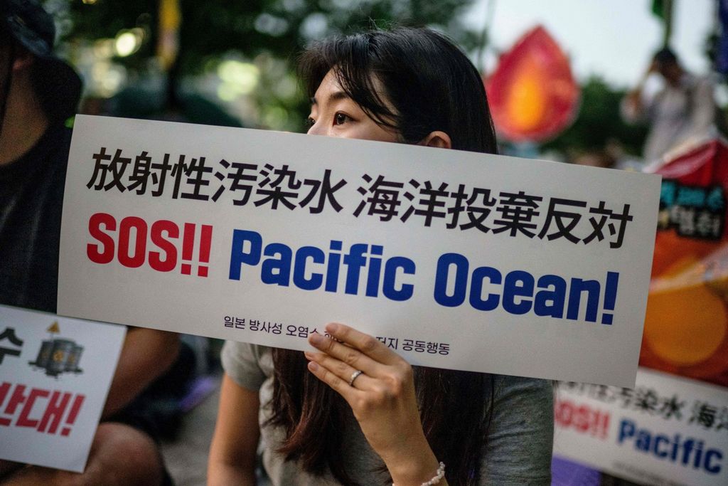 Seorang aktivis membawa poster bertuliskan "SOS!! Pacific Ocean!" saat ia dan rekan-rekannya berunjuk rasa di balai kota di Seoul, Korea Selatan, Selasa (22/8/2023).