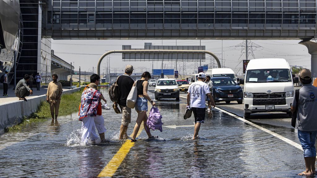 Residents cross puddles of water on the Sheikh Zayed toll road in Dubai, United Arab Emirates, Thursday (18/4/2024).