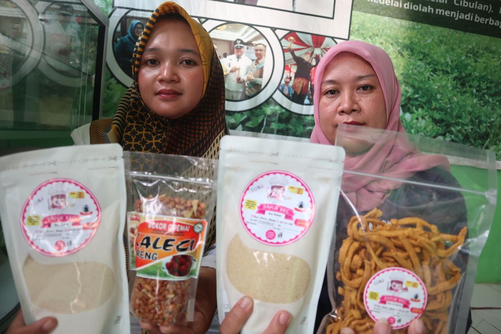 Rima Darmayanti (kiri) dan Wati Kuswati menunjukkan produk olahan kedelai, seperti susu bubuk dan kacang goreng di Desa Cibulan, Kecamatan Cidahu, Kabupaten Kuningan, Jawa Barat, Senin (21/2/2022).
