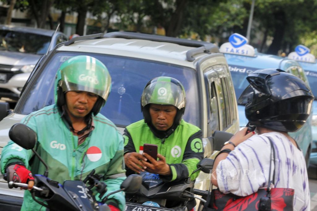 Pengojek daring mengecek pesanan di sekitar Stasiun Palmerah, Jakarta, Jumat (12/5/2023). BPJS Ketenagakerjaan mendorong pekerja informal seperti pengojek daring untuk jadi peserta BPJS Ketenagakerjaan. 