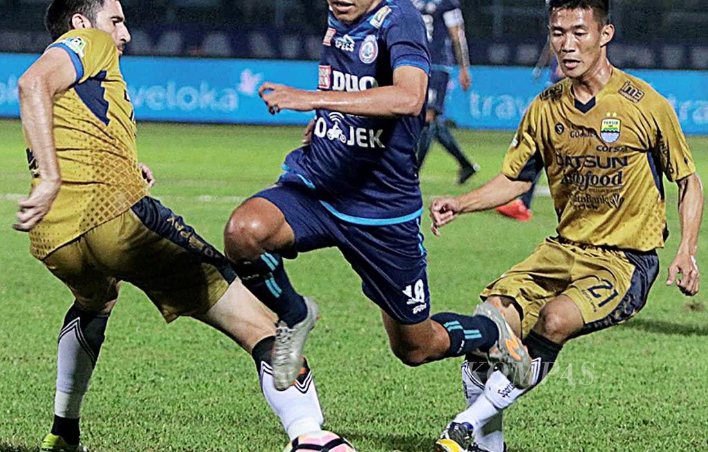 Gelandang   Arema FC, Adam Alis Setyano (tengah), melompati hadangan bek Persib Bandung, Vladimir Vujovic (kiri), dalam laga lanjutan Go-Jek Traveloka Liga 1, Sabtu (12/8), di Stadion Kanjuruhan, Malang, Jawa Timur. Laga berakhir 0-0.