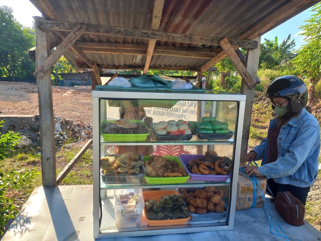 Seorang konsumen membeli kue basah yang dijajakan di salah satu sudut Kota Kupang, Nusa Tenggara Timur, Selasa (12/4/2022).