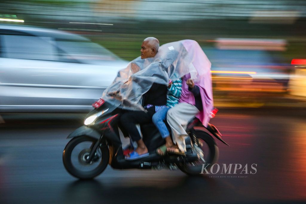 Warga menggunakan jas hujan saat hujan deras mengguyur kawasan Pisangan, Tangerang Selatan, Banten, Jumat (15/7/2022). Badan Meteorologi, Klimatologi, dan Geofisika (BMKG) telah mengeluarkan peringatan dini cuaca ekstrem yang berpotensi terjadi di sejumlah wilayah di Indonesia.