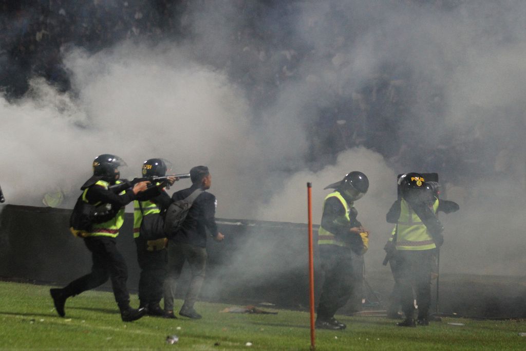 Aparat keamanan menembakkan gas air mata untuk menghalau suporter yang masuk lapangan seusai pertandingan sepak bola BRI Liga 1 antara Arema dan Persebaya di Stadion Kanjuruhan, Malang, Sabtu (1/10/2022).